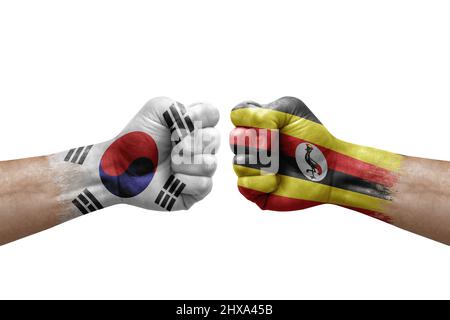 Two hands punch to each others on white background. Country flags painted fists, conflict crisis concept between south korea and uganda Stock Photo