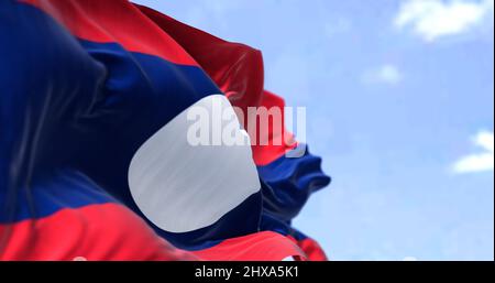 Detail of the national flag of Laos waving in the wind on a clear day. Laos is a socialist state and the only landlocked country in Southeast Asia. Se Stock Photo