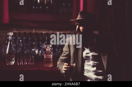 Old traditional whiskey drink - gentlemans beverage. Hipster male with stylish beard drinking beer sitting at the bar. Stock Photo