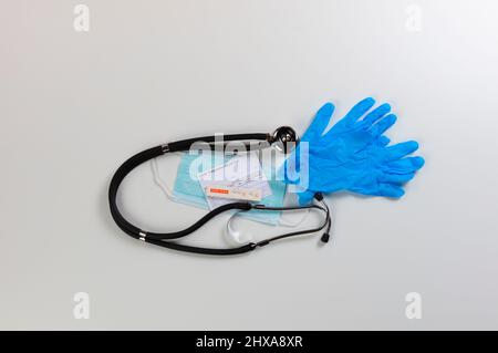 Rapid test device for covid 19 showing negative test result plus personal facemask, stethoscope, latex gloves and vaccination card on a white backgrou Stock Photo