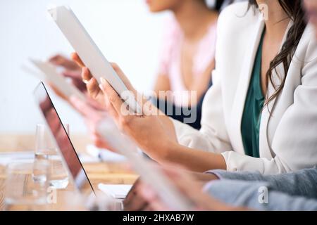 Wireless freedom in the boardroom. Cropped shot of a group of businesspeople using their wireless devices during a meeting. Stock Photo