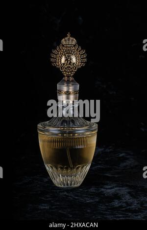 Royalty styled glass golden perfume bottle on a black velvet background. Stock Photo