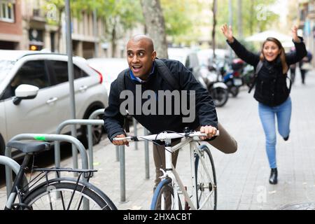 Man stealing bicycle, woman owner running after Stock Photo