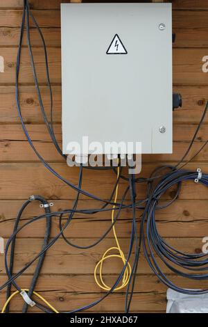 Electrical panel on a wooden wall with unprotected wires. Stock Photo