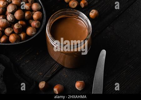 Chocolate spread or nougat cream with hazelnut set, on black wooden table background Stock Photo