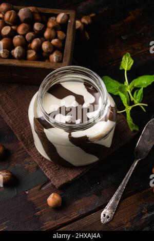 Chocolate hazelnut in jar with nuts set, on old dark wooden table background Stock Photo