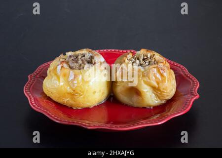 Two baked apples on red plate on the black background Stock Photo