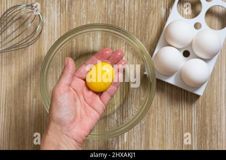 Hand of woman holding the one raw chicken yolk after separation egg Stock Photo