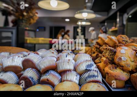 Artisanal cupcakes on display in a bakery in Pamplona, Spain with customers in the background, wearing masks for COVID 19 Stock Photo