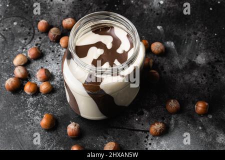 Hazelnut spread with nuts set, on black dark stone table background Stock Photo