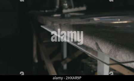 Forge. Smithy. Glass cutting and processing for fireplace doors. Circular glass cutter. Worker cut glass with glass cutting diamond. Polish an angle g Stock Photo