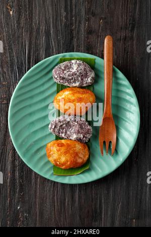 Gemblong or Kue Gemblong is Sticky Rice Cake Caoted with Liquid Palm Sugar, Indonesian Popular Street Food. Served with Tea Stock Photo