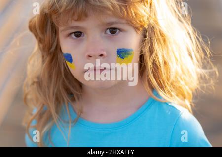 Ukraine flag on kids cheek. No war, stop war, russian aggression. Little ukrainian patriot. Stock Photo