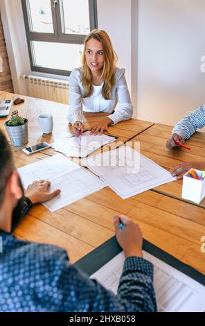 Businesswoman in a work meeting looking blueprints Stock Photo