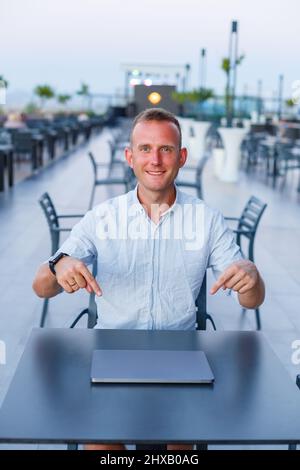 A successful businessman works on a laptop on a hotel terrace and finds time to remotely manage employees while on holiday at an exotic resort. Man in Stock Photo