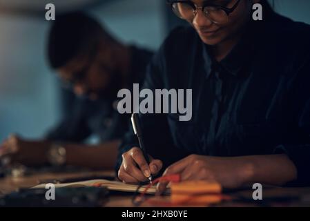 Its never too late to get your computer hardware refurbished. Shot of a young technician writing in a notebook while repairing computer hardware. Stock Photo