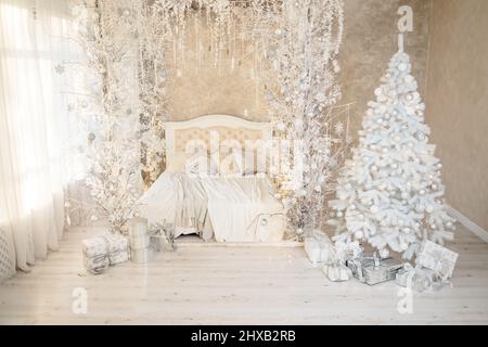 New Year's holiday, mood, Stylish New Year's minimalistic interior, Gifts and wrapped gifts under the Christmas tree. large white bedroom with white b Stock Photo