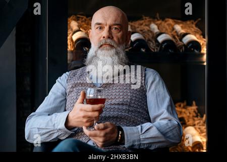 elderly winemaker with a glass of red wine. Stock Photo