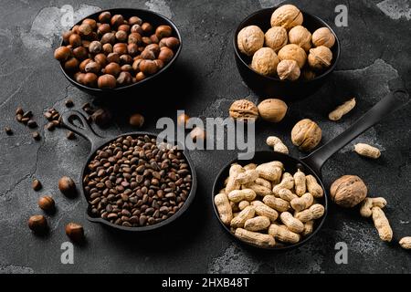 Assortment of nuts in shells, peanut, walnut, pine nuts and hazelnut set, on black dark stone table background Stock Photo