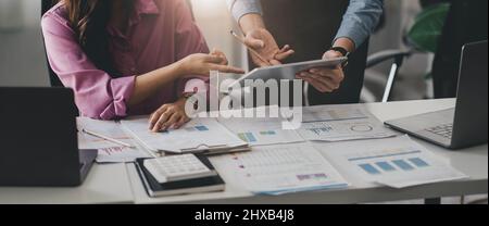 Close up business adviser partnership coworkers using a tablet to chart company financial statements report and profits work progress and planning in Stock Photo