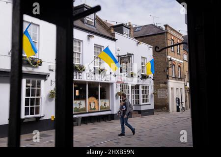 As the war in Ukraine enters its third week, Ukrainian flags hang above 'The Eel Pie' pub on Church Street, Twickenham, on 10th March 2022, in London, England. The initiative was organised by The Church Street of Twickenham Association showing solidarity and sympathy with local Ukrainians, saying: 'Showing solidarity with our Ukrainian brothers and sisters. We feel for you and your horrific ordeal. Stay strong!' Stock Photo