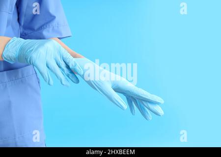 Woman doctor putting on gloves on blue background Stock Photo