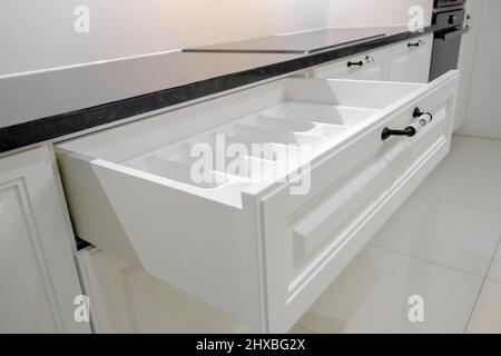 Side view modern and elegant kitchen with white drawers, open kitchen drawer with dish drying rack, selective focus Stock Photo