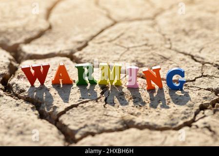 Text Warming on arid cracked soil. Concept of climate change. Stock Photo