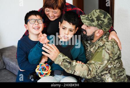 Happy soldier man hugging his family after returning from military service at home - Family moments and war concept - Main focus on mother face Stock Photo