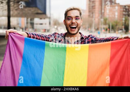 Gay man having fun holding lgbt rainbow flag outdoor - Pride concept Stock Photo