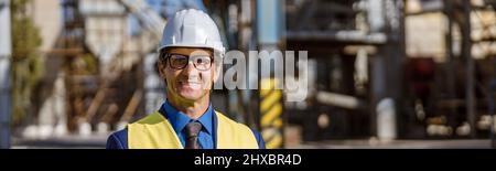 Joyful male engineer using notebook outdoors at factory Stock Photo