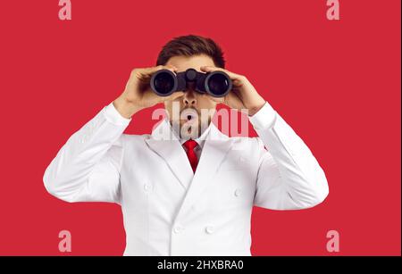 Funny man in suit holding binoculars and looking at sale discounts with surprise Stock Photo