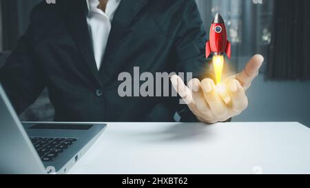 Male hand holding rocket icon that takes off,  rocket is launching and flying out, Business start up, Icon marketing on modern virtual interface.Start Stock Photo