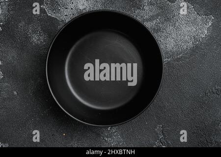 black pottery bowl, with copy space for text or food, with copy space for text or food, top view flat lay , on black dark stone table background Stock Photo