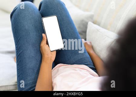 Midsection of african american girl using smart phone while lying on sofa at home, copy space Stock Photo