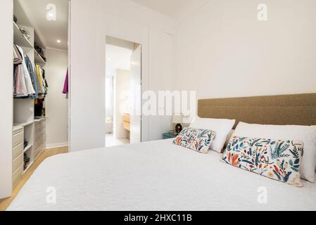 King size bed with flowery cushions in bedroom with dressing room and en-suite bathroom Stock Photo