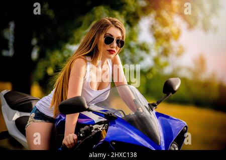 a beautiful long-haired blonde woman on a motorcycle Stock Photo