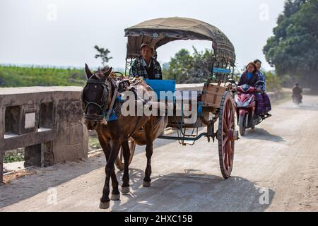 Mandalay, Myanmar - January 11, 2016: An unidentified man riding a horse drawn carriage on the outskirts of Mandalay, Myanmar. Stock Photo