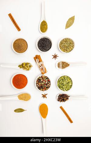 Top view, set of different culinary spices in white ceramic bowls and spoons, on white background. Stock Photo