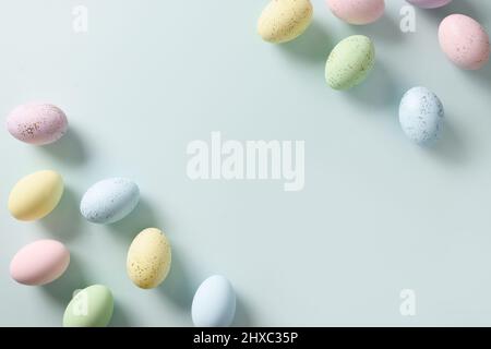 Happy Easter greeting card as banner with pastel eggs on blue background. View from above. Flat lay. Copy space. Stock Photo
