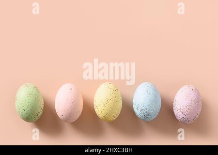 Colorful pastel eggs on pink background. Flat lay. Happy Easter greeting card with copy space. Top view. Stock Photo