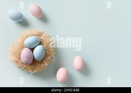 Easter eggs in nest on blue background. View from above. Copy space. Happy Easter greeting card with copy space. Top view. Stock Photo