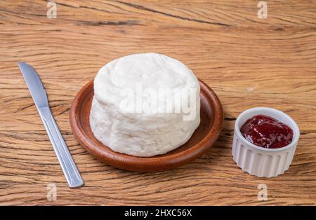 Frescal cheese, typical brazilian fresh white cheese with strawberry jam over wooden table. Stock Photo