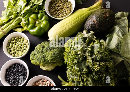 Directly above shot of various green vegetables, fruit, herb with seeds and legumes on table Stock Photo