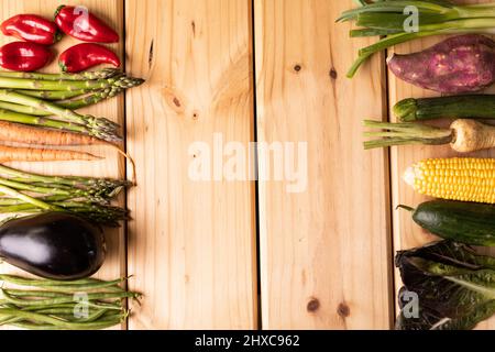 Overhead view of empty space by various vegetables arranged side by side on wooden table Stock Photo