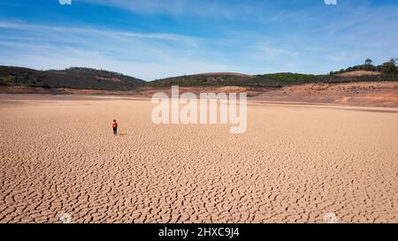 Silhouette of a man on a sandy cracked empty not fertile land during a drought. The concept of ecological catastrophe on the planet. Stock Photo