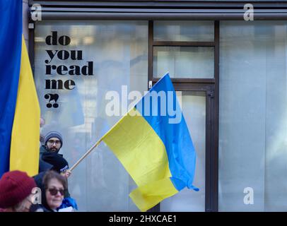 Helsinki, Finland - March 5, 2022: Demonstrators with a Ukrainian flag in a rally against Russia’s military actions and occupation of Ukraine with Do Stock Photo