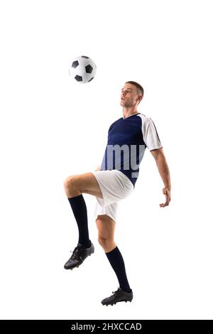 Full length of skilled caucasian male player kicking ball against white background Stock Photo