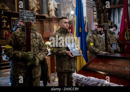 Lviv, Ukraine. 11th Mar, 2022. Ukrainian soldiers seen holding photos of dead soldiers and crosses during the funeral service. The funeral of the three Ukrainian soldiers killed during the Russian Invasion of Ukraine, has been held in Lviv, at Saints Peter and Paul Garrison Church (also known as Jesuit Church). Credit: SOPA Images Limited/Alamy Live News Stock Photo