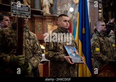 Ukrainian soldier seen holding a photo of a dead soldier and a cross during the funeral service. The funeral of the three Ukrainian soldiers killed during the Russian Invasion of Ukraine, has been held in Lviv, at Saints Peter and Paul Garrison Church (also known as Jesuit Church). (Photo by Valeria Ferraro / SOPA Images/Sipa USA) Stock Photo